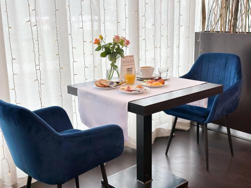 布拉迪斯拉发莫德纳酒店的一张桌子,上面有盘子食物和两把蓝色的椅子