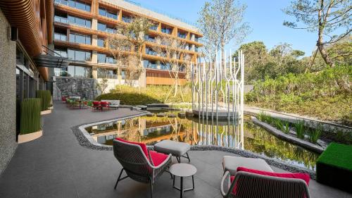 番路乡阿里山英迪格酒店的一座建筑前的庭院,配有椅子和池塘