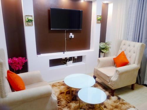 Langata RongaiSpringStone executive apartment Rm 4的客厅配有2把椅子和平面电视