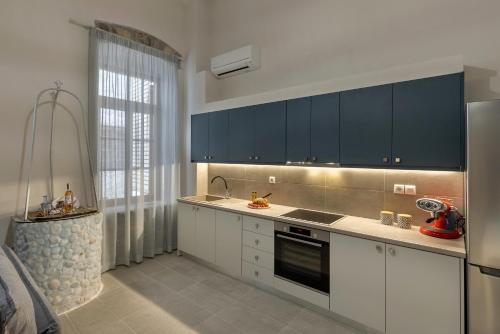 埃尔莫波利斯Grammata Suites的厨房配有白色橱柜和黑色家电