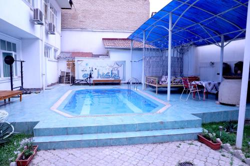 塔什干Art Hostel的后院的带蓝伞的游泳池