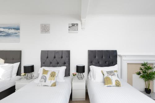 Enfield LockSkyvillion - London Enfield 4 Bedroom Lush House Free Parking Garden的卧室内的两张床,配有白色床单和枕头