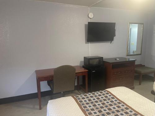 小石城Economy Inn Little Rock的一间卧室配有书桌、一张床和一台电视。