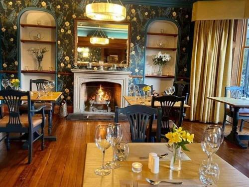 圣菲伦斯Achray House Restaurant with Rooms的一间带壁炉的用餐室和一张带酒杯的桌子
