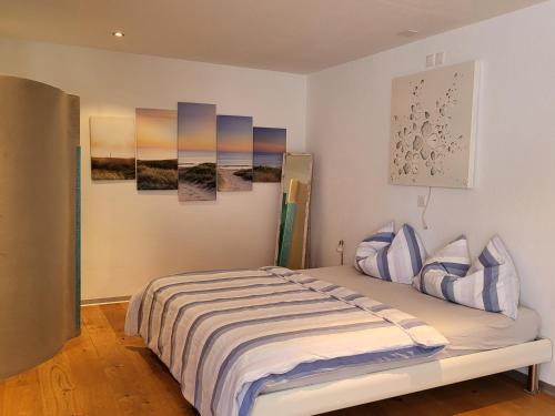 施皮茨Oase zum SEIN的一间卧室配有一张床,墙上挂着一些绘画作品