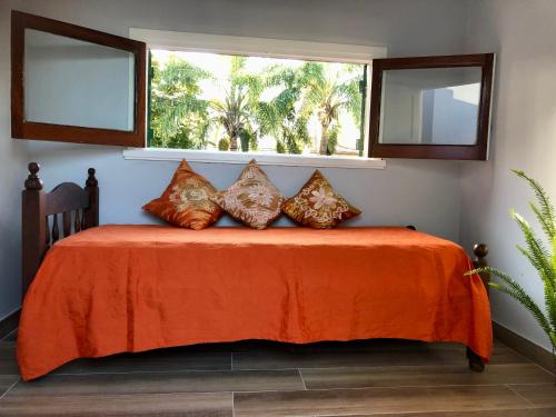 马德普拉塔Chalet Pura Vida的一张带橙色毯子的床和两个窗户