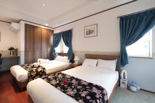 弘前市Fantastic Story的蓝色窗帘的酒店客房内的两张床
