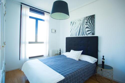 马德里Apartament Glorieta Puerta de Toledo的蓝色和白色的卧室设有床和窗户