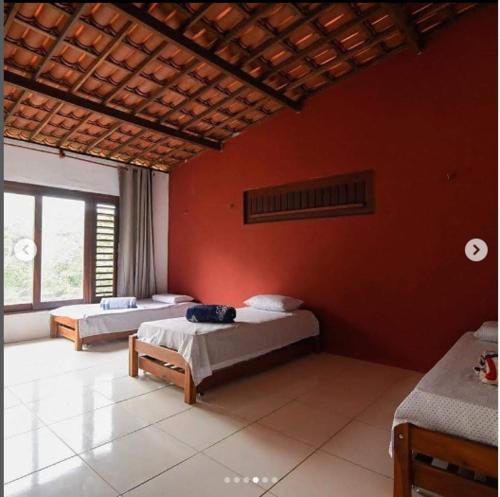 瓜拉米兰加Pousada Raízes Guaramiranga的一间卧室设有两张床和红色的墙壁