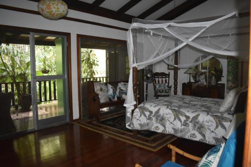 耐莉湾奥斯卡尔雨林住宿加早餐旅馆的一间卧室设有天蓬床和门廊。