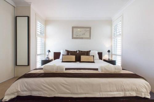 珀斯Beach View Apartment in Cottesloe的白色卧室设有一张大床和两个窗户