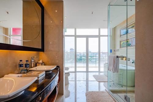 海口海口星海湾铂尔曼酒店的一间带两个水槽和玻璃淋浴间的浴室