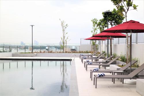巴生KSL ESPLANADE HOTEL with HOT SPRING的大楼旁的带长椅和遮阳伞的游泳池