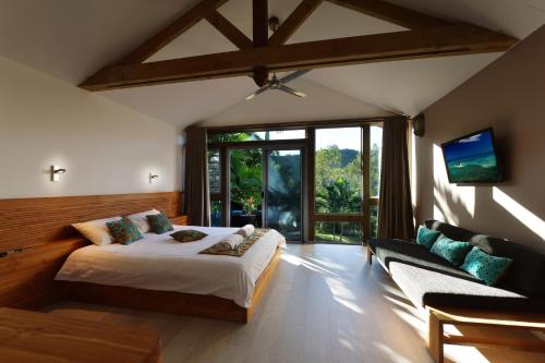 布拉伊Betikure Parc Lodge的一间卧室配有一张床、一张沙发和一台电视。