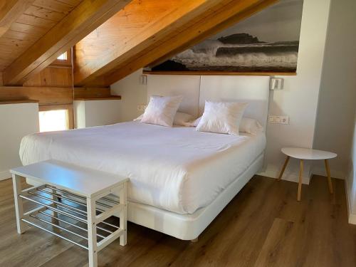 蒙达卡Apartamentos Mundaka Surf Camp的卧室配有白色的床和桌子