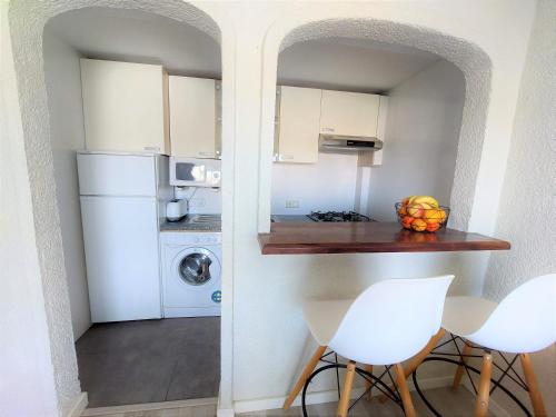 哈维亚Apartamentos Strand Jávea的厨房配有白色冰箱、桌子和椅子