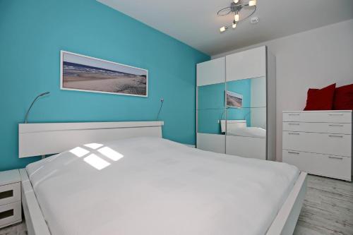 海利根达姆Residenz von Flotow Wohnung 13的卧室配有白色的床和蓝色的墙壁