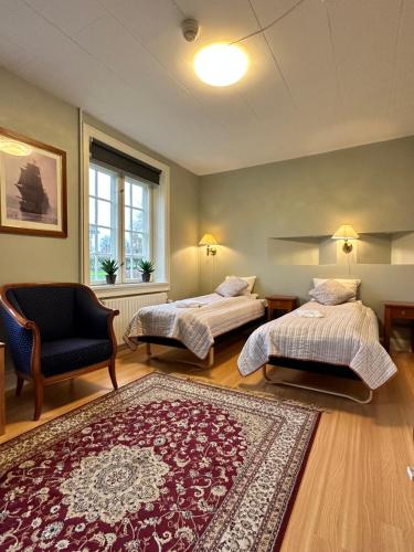 海松Forvalterboligen的卧室配有两张床、椅子和地毯。