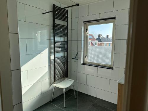 栋堡Appartementen Beatrix的白色瓷砖浴室设有椅子和窗户