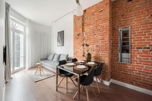 华沙East Warsaw Modern Apartment的一间设有砖墙和桌椅的客厅