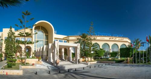 迦玛特迦太基海水浴酒店的一座大建筑,前面有一堆棕榈树