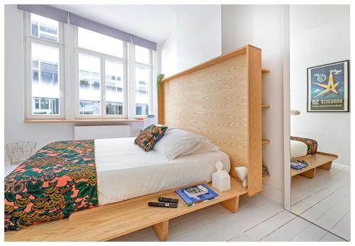 布鲁塞尔幸福旅馆的一间卧室配有一张带木制床头板和窗户的床。