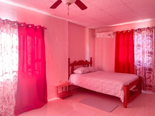 西班牙港Apartment at Trincity Central Road的卧室拥有粉红色的墙壁,配有红色窗帘