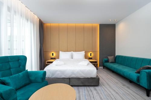 巴统The Grandeur Hotel的酒店客房带一张床和两张蓝色的沙发