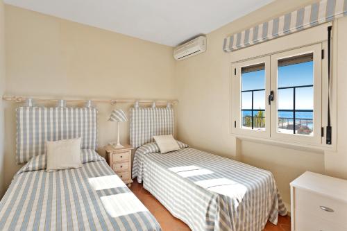 马贝拉J96 Cabopino的一间卧室设有两张床和一个海景窗户。