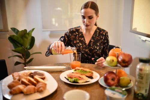 雅典Anixi Hotel by AP的把一杯橙汁倒在餐桌上的女人