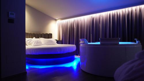 圣安杰洛城Leoni Hotel & Private Spa - LOVE HOTEL的酒店客房配有一张床和一张带蓝色灯光的书桌