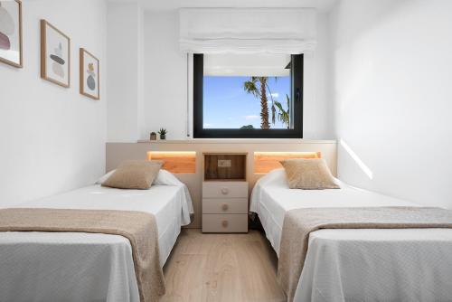 拉梅特拉·德·玛尔Garbí by enjoy Rocas Doradas的白色客房的两张床,设有窗户
