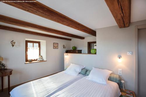 BreitenauA l'ombre du verger的卧室配有一张白色大床和木制天花板