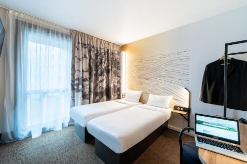 阿斯克新城B&B HOTEL Lille Grand Stade的酒店客房,配有两张床和一台笔记本电脑