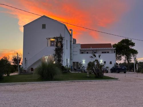 莱西纳Agriturismo Masseria Cannella的白色的建筑,背面有日落