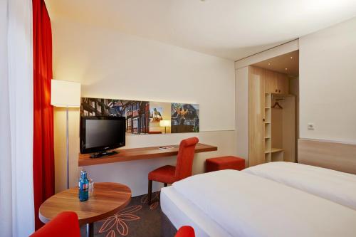 戈斯拉尔戈斯拉尔H+酒店的酒店客房设有一张床和一张带电视的书桌。