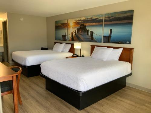 湖城湖城戴斯I-10汽车旅馆的酒店客房设有两张床,墙上挂有绘画作品