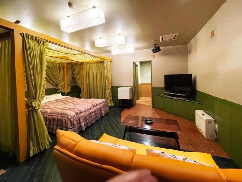 YobitoHotel ARUN的酒店客房设有沙发、床和电视。