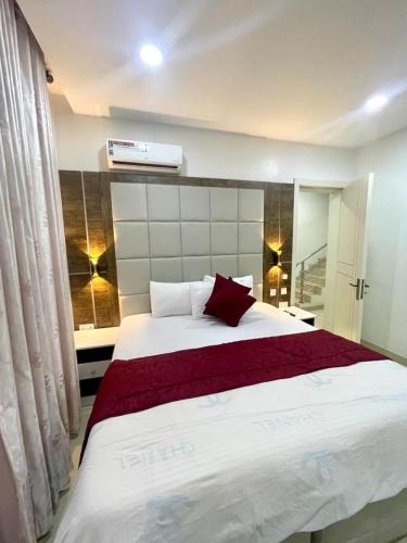 拉各斯Tastefully Furnished 2-Bedroom Duplex的卧室配有一张大白色床和红色枕头