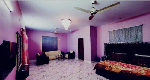 卡拉奇Best Couple Coprtive Guest House的一间卧室设有紫色的墙壁、一张床和一张沙发