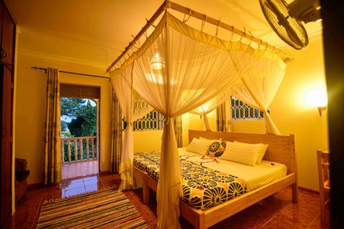 恩德培Cycad Entebbe Guest House的一间卧室设有天蓬床和窗户。