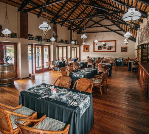 皮尔格林斯雷斯特Mount Sheba Rainforest Hotel & Resort的一间在房间内配有桌椅的餐厅