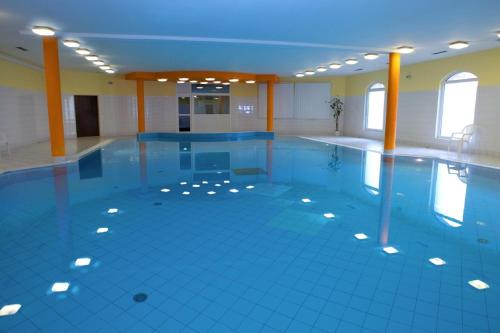 普鲁洪尼斯小花酒店的设有一个大型游泳池,铺有蓝色的瓷砖地板,并拥有窗户。