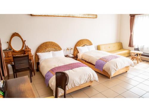 MitsuneHachijojima Hotel Resort Sea Pillows - Vacation STAY 53304v的一间卧室配有两张床和一张桌子及椅子