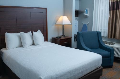 麦迪逊AmericInn by Wyndham Madison WI的酒店客房,配有一张床和一张蓝色椅子