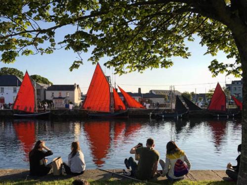 戈尔韦Beautiful one bedroom Apartment In Galway City的一群人坐在河边,有红色的帆船