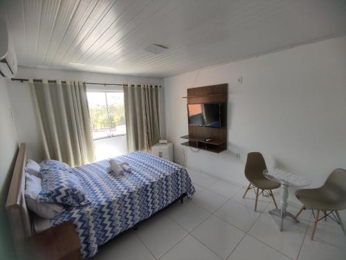 皮拉尼亚斯Pousada Marihá的一间卧室设有一张床、一台电视和一个窗口。