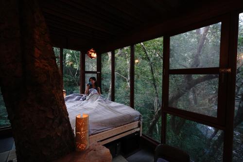 名户Treeful Treehouse Sustainable Resort的窗户房间里一张床上的女人