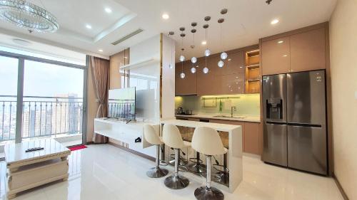 胡志明市Vinhome Central Park Apartment的厨房配有带凳子的柜台和冰箱。