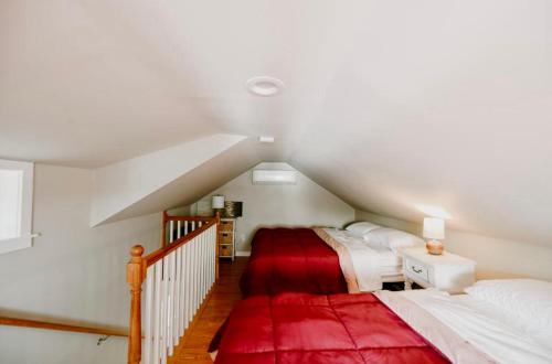 WinthropLittle Landing Cottage On Cobbossee Lake的阁楼卧室配有两张床和红色地毯。